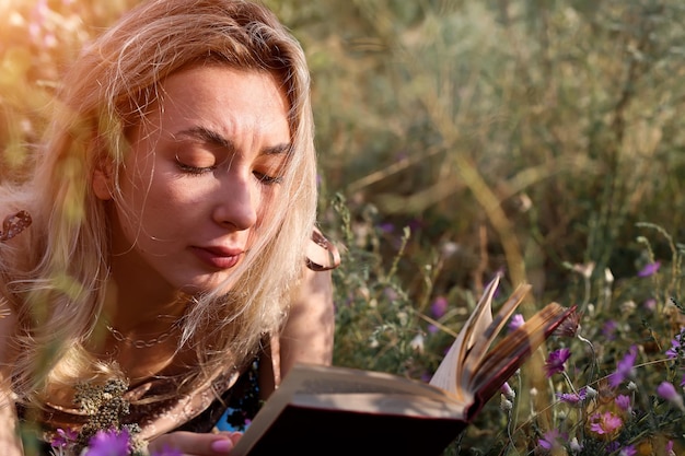 Photo young woman reads a book in the field in nature summer evening