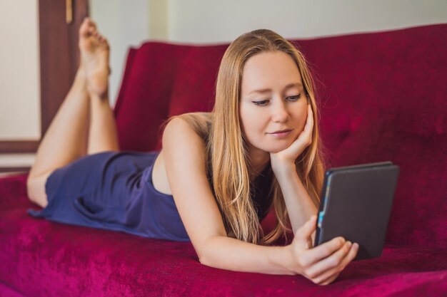 Young woman reads ebook at home on the couch