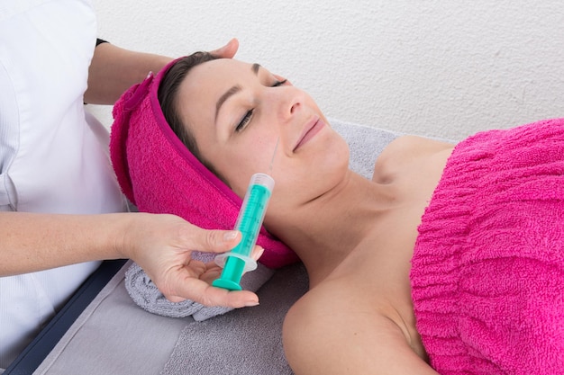 Young woman receiving a botox injection in her cheek