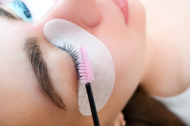 Young woman receiving eyelash lamination procedure in a beauty salon, close up