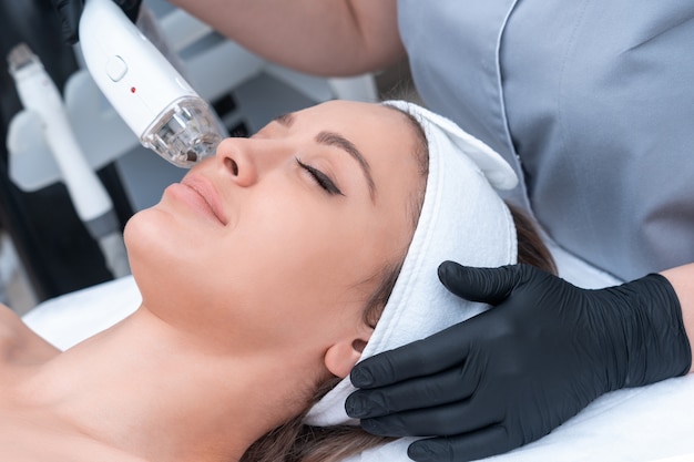 Giovane donna che riceve il trattamento laser nella clinica di cosmetologia