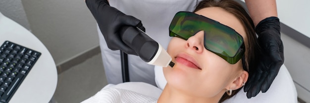 Giovane donna che riceve il trattamento laser nella clinica di cosmetologia