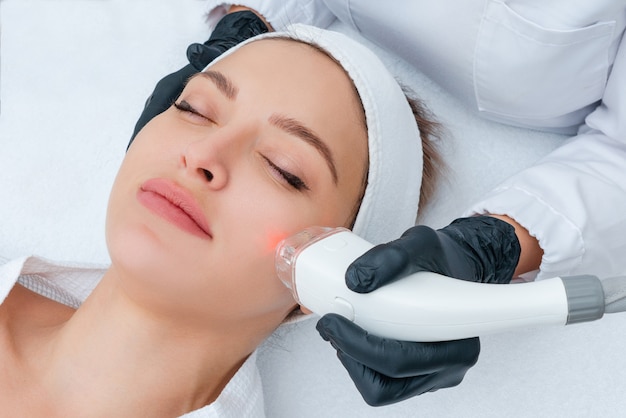 Young woman receiving laser treatment in cosmetology clinic