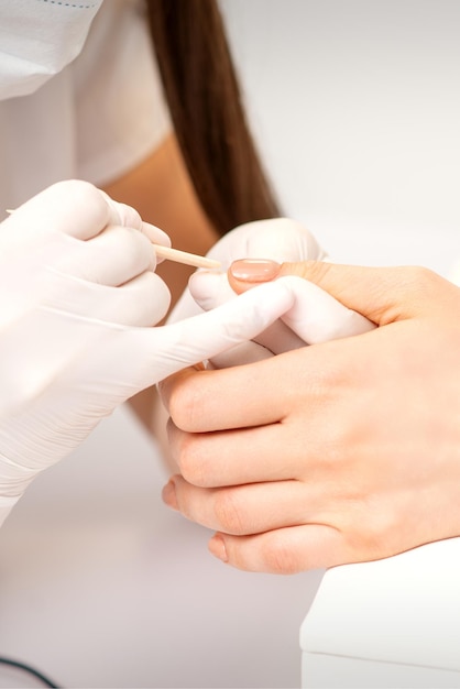 Young woman receiving pink or beige nail polish in a beauty salon.