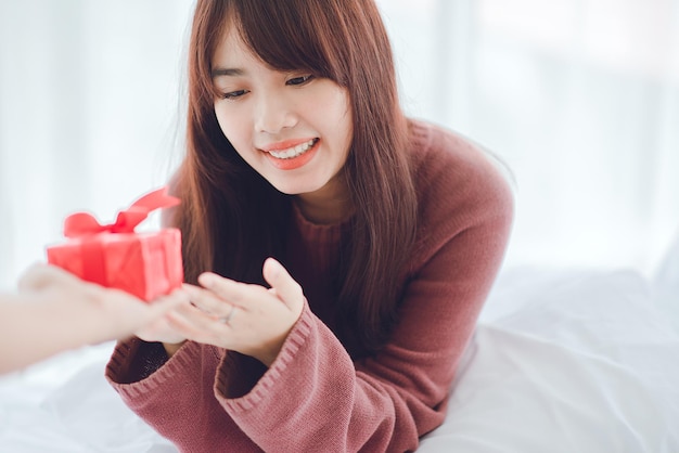 Young woman receiving a surprise gift box from her boyfriend at home