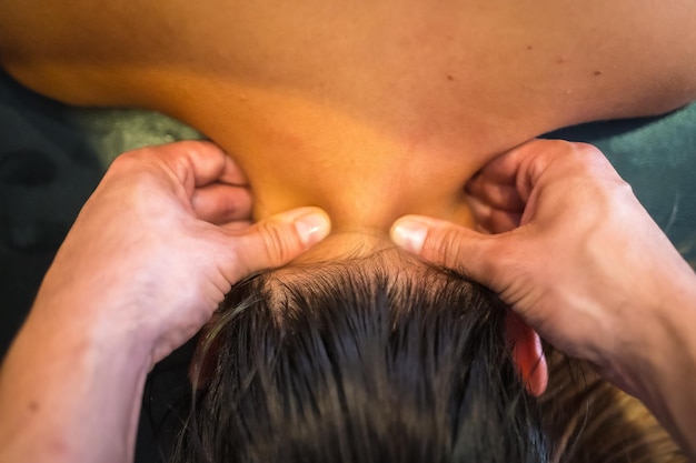 Una giovane donna che riceve un massaggio al collo con due dita da un fisioterapista physio osteopatia