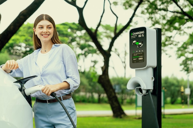 Photo young woman recharge ev electric vehicle battery from ev charging station exalt