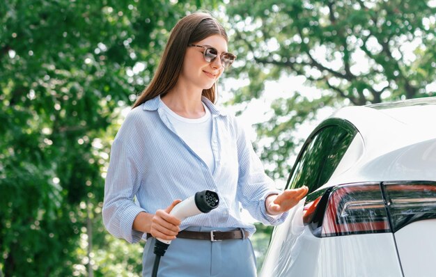 写真 道路旅行中に電動車のバッテリーを充電する若い女性