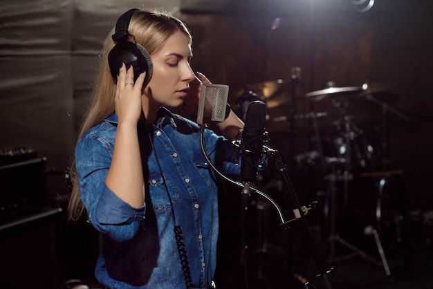 Young woman recording a song in the studio.