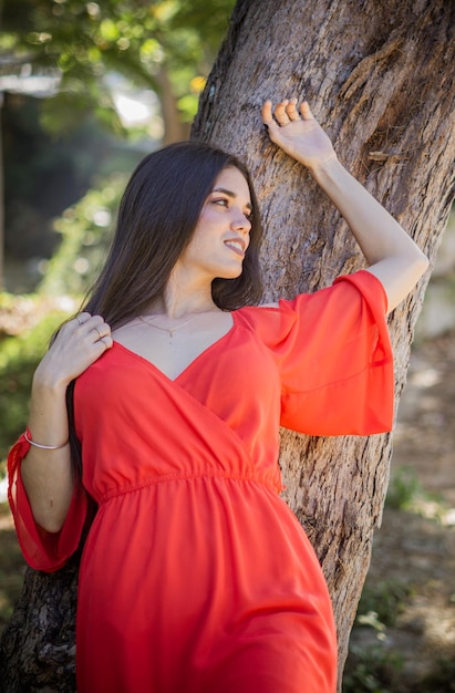 Giovane donna in abito rosso in una foresta che si gode la natura