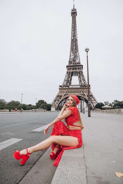 夏の晴れた日にパリのエッフェル塔の近くで赤いドレスを着た若い女性