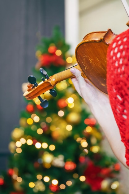 Young woman in red dress playing violin, rear view, background blurred