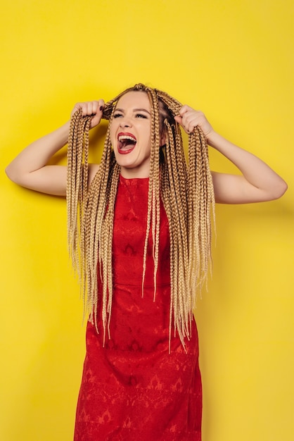 Young woman in red dress pulls herself for pigtails and screams