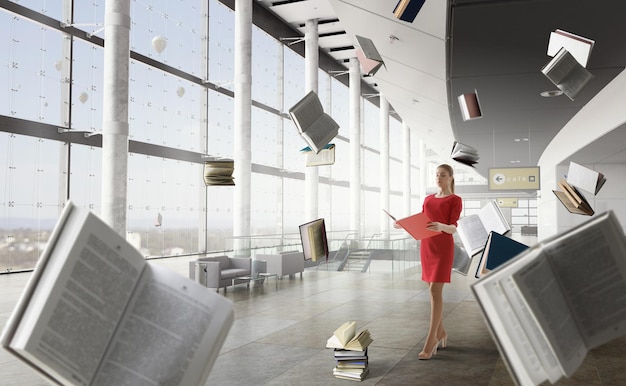 Young woman in a red dress reading a book with other books flying around. Mixed media