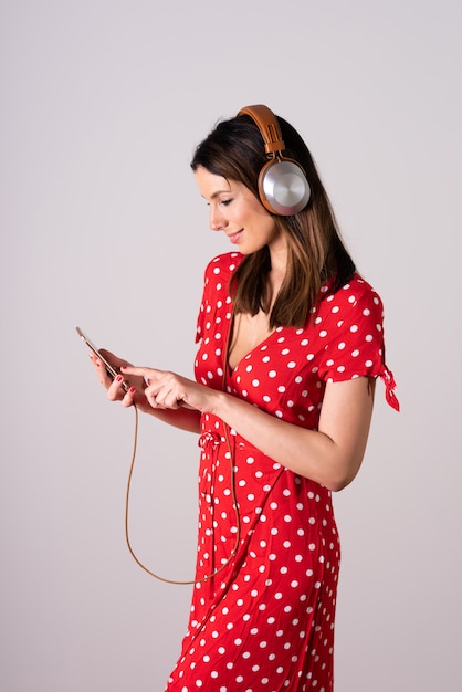 Молодая женщина в красном платье с помощью своего смартфона