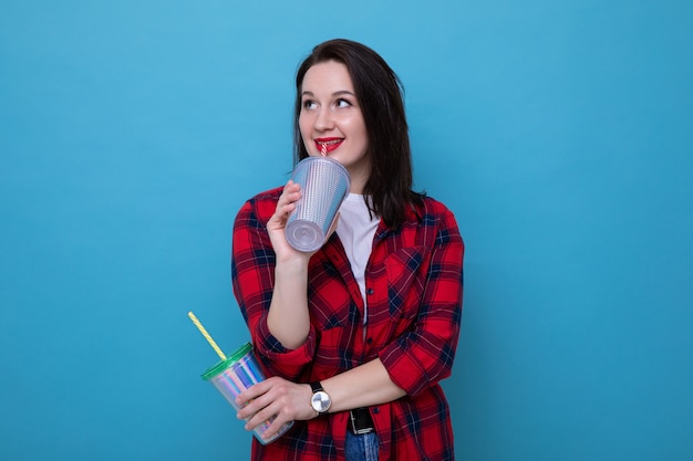 A young woman in a red shirt holds two cocktail glasses