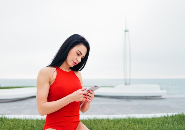 Young woman in red swimsuit using a smartphone