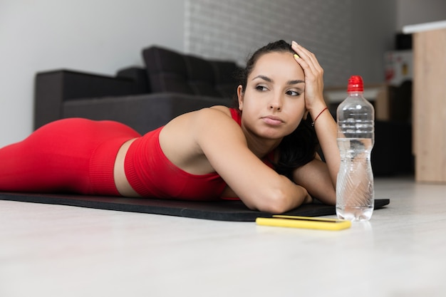 Giovane donna in tuta rossa facendo esercizio o yoga a casa