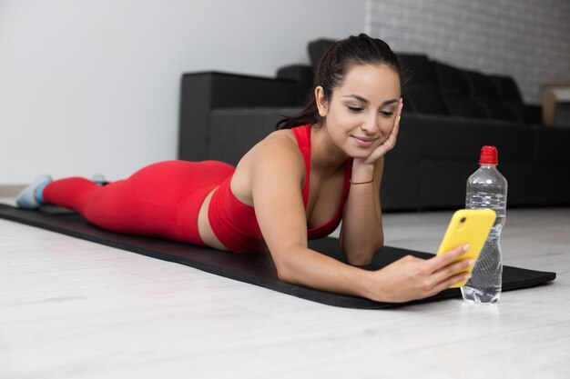 Young woman in red tracksuit doing exercise or yoga at home