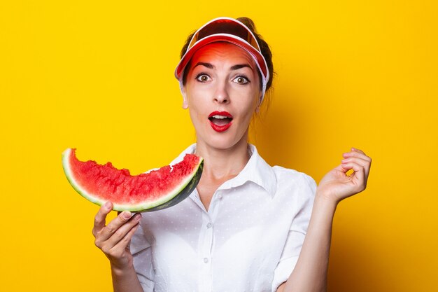 Young woman in red visor holding a slice of watermelon