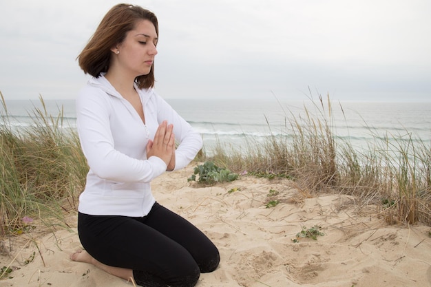 Молодая женщина отдыхает на пляже с позой йоги