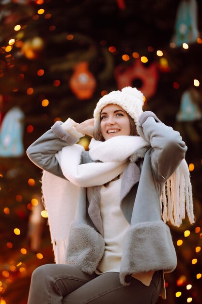 Young woman relaxing drinking coffee in festive christmas fair winter holidays lights around