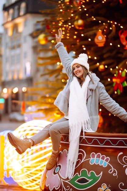 Young woman relaxing drinking coffee in Festive Christmas fair Winter holidays Lights around