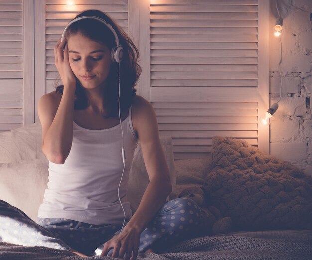 그녀는 음악을 듣고 그녀의 침대에서 편안한 젊은 여자