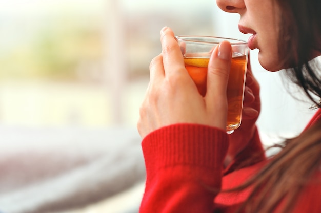 Tazza di tenuta di rilassamento della giovane donna con il tè del limone