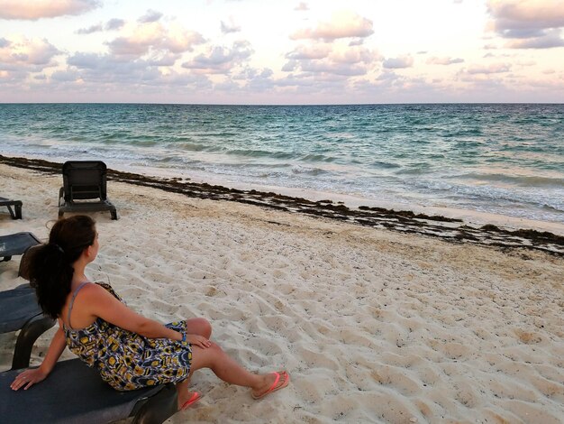 Young woman relaxing on lounge chair on sandy beach