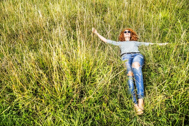 牧草地でリラックスした若い女性