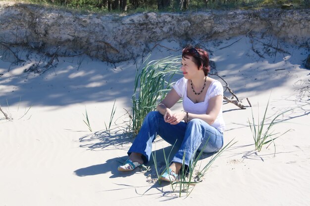 Young woman relaxing on a sand near the Baltic sea in warm spring day.