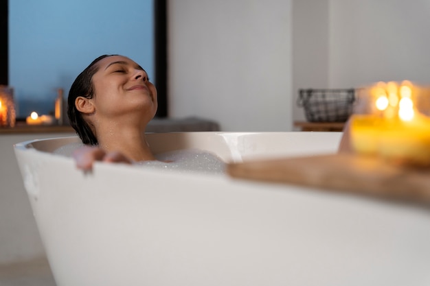 Photo young woman relaxing and smiling while taking a bath