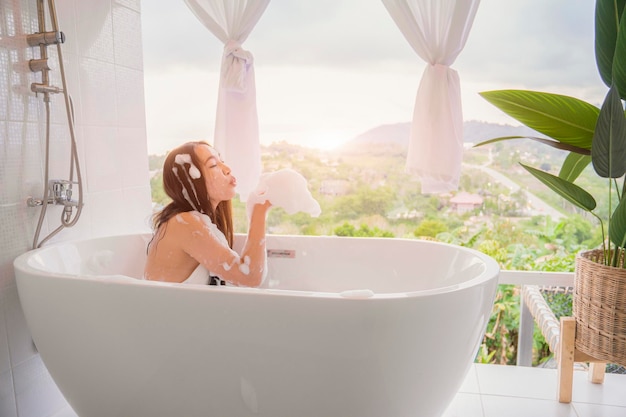 Young woman relaxing and takes bubble bath in bathtub with foam