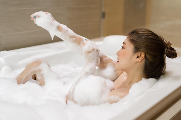 Young woman relaxing and takes bubble bath in bathtub with foam