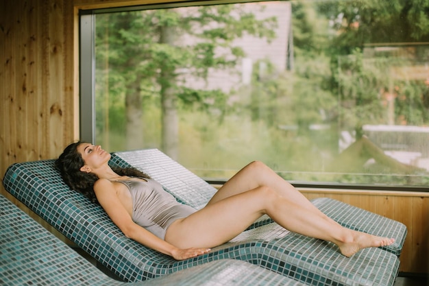 Young woman relaxing on the tepidarium bed in the spa