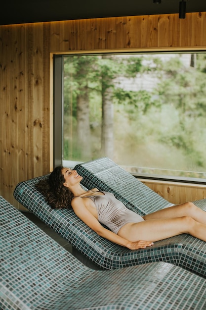 Young woman relaxing on the tepidarium bed in the spa