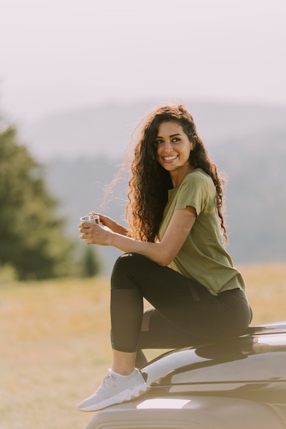 Young woman relaxing on a terrain vehicle hood at countryside