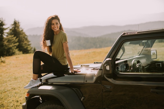 Young woman relaxing on a terrain vehicle hood at countryside