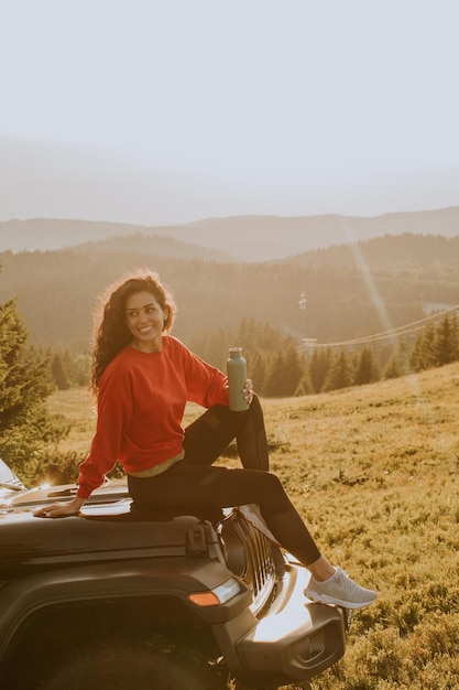 Young woman relaxing on a terrain vehicle hood at countryside