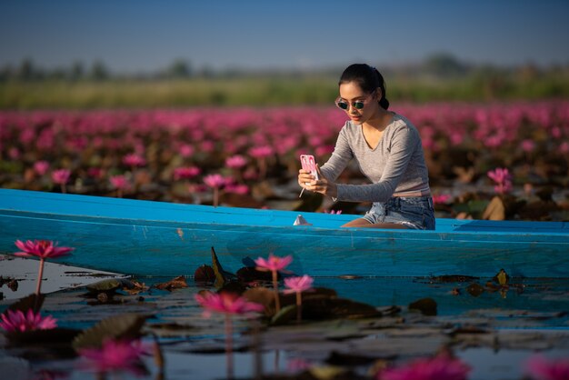 写真 赤い蓮の海で美しい蓮の花畑でリラックスできる若い女性
