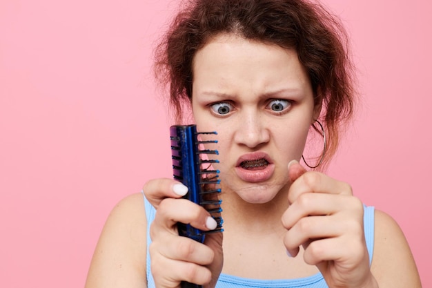 Молодая женщина удаляет волосы на расческе неудовлетворенность изолированным фоном без изменений