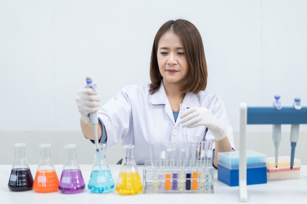 A young woman researcher, doctor, scientist, or laboratory assistant working with plastic medical tubes to research, examine scientific experiments in a modern laboratory. Education stock photo