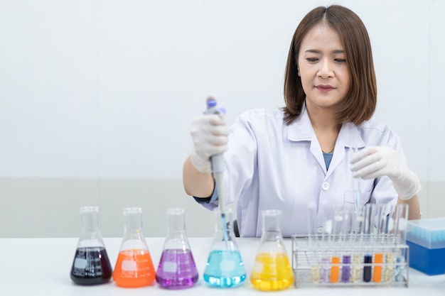 A young woman researcher, doctor, scientist, or laboratory assistant working with plastic medical tubes to research, examine scientific experiments in a modern laboratory. Education stock photo