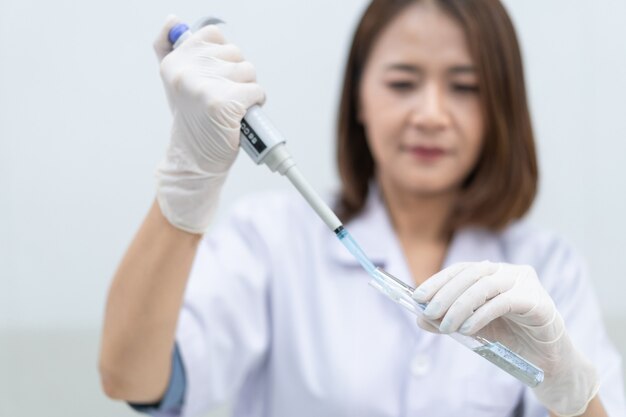 A young woman researcher, doctor, scientist, or laboratory assistant working with plastic medical tubes to research, examine scientific experiments in a modern laboratory. Education stock photo