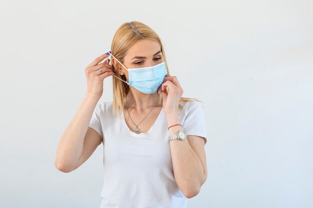 Young woman in respiratory mask. Masked attractive woman putting on protective mask. Cold, flu, virus, tonsillitis, acute respiratory disease, quarantine, epidemic. Covid - 19, coronavirus prevention