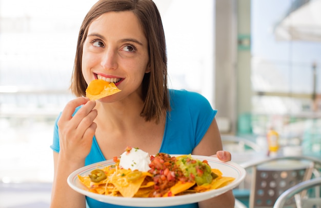 young woman in a restaurant having nachos