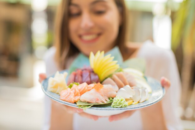 寿司を持つレストランで若い女性