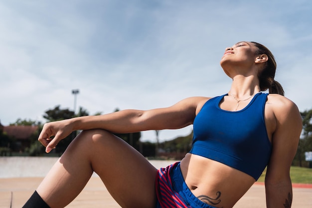 A young woman resting after exercising in an urban park.