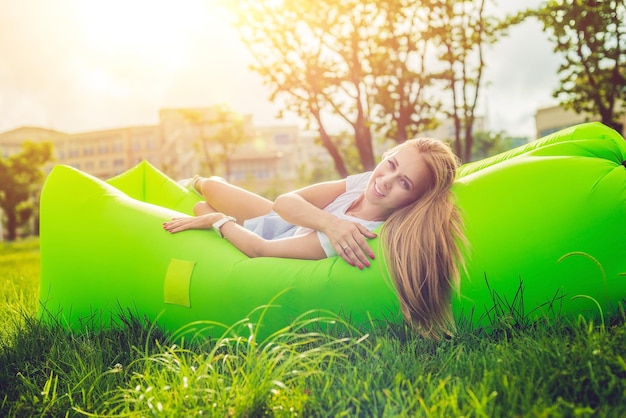 Young woman resting on an air sofa in the park.. lamzac